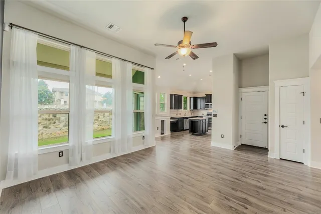 a view of a livingroom with furniture a ceiling fan and wooden floor