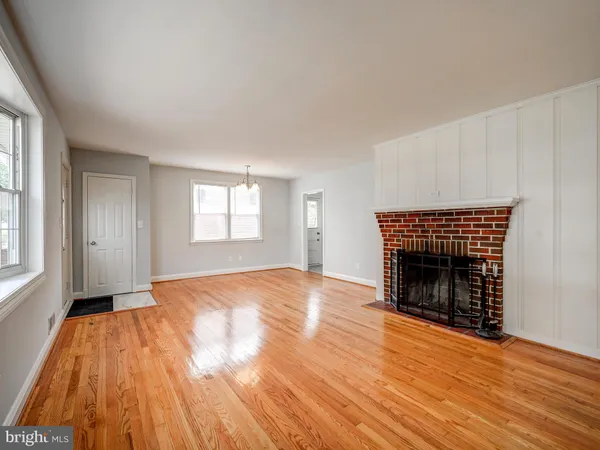 an empty room with wooden floor fireplace and windows