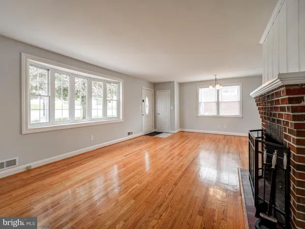 a view of an empty room with wooden floor and window