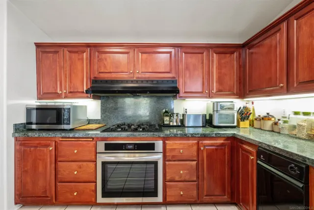 a kitchen with granite countertop a stove top oven microwave and cabinets