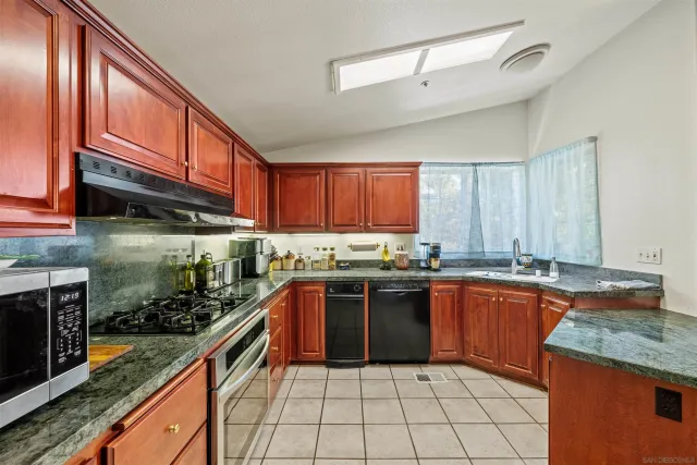 a kitchen with stainless steel appliances granite countertop a stove a sink and a microwave