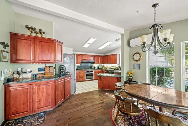 a room with stainless steel appliances kitchen island granite countertop a stove a sink dishwasher and a dining table with the view of kitchen