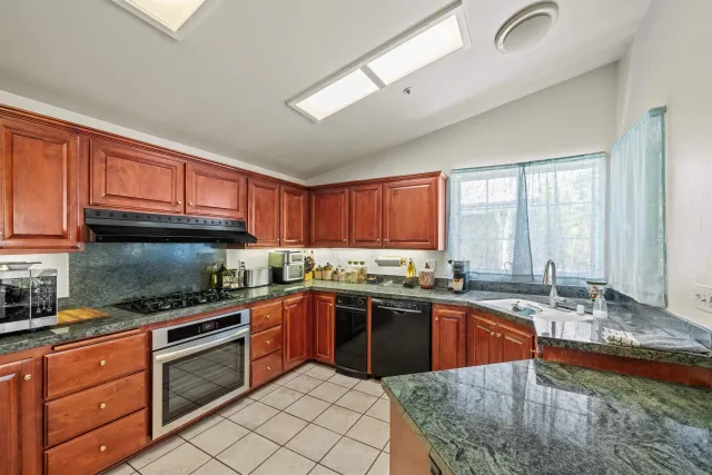 a kitchen with stainless steel appliances granite countertop a sink a stove counter space and cabinets