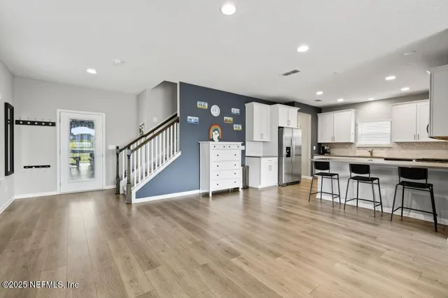a kitchen with stainless steel appliances granite countertop a refrigerator a sink and white cabinets