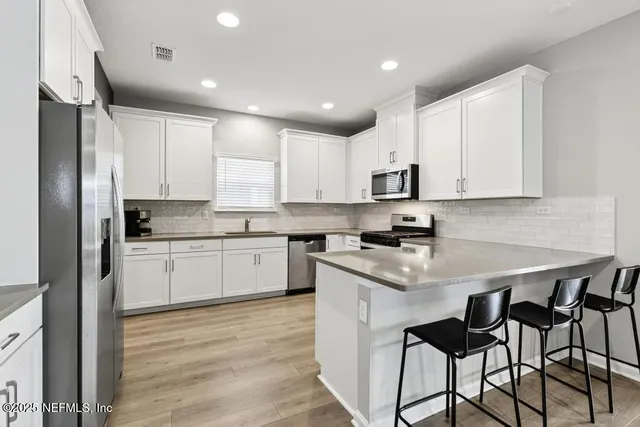 a kitchen with stainless steel appliances granite countertop white cabinets sink and a granite counter top