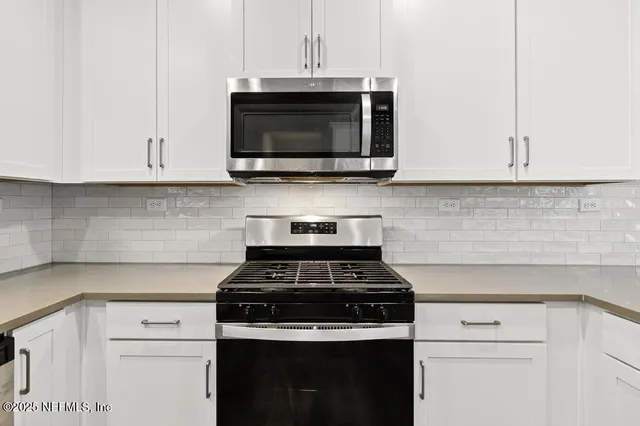 a kitchen with granite countertop white cabinets and stainless steel appliances