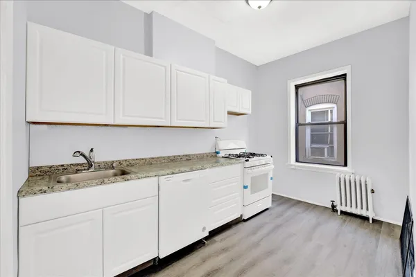 a kitchen with granite countertop white cabinets and a stove