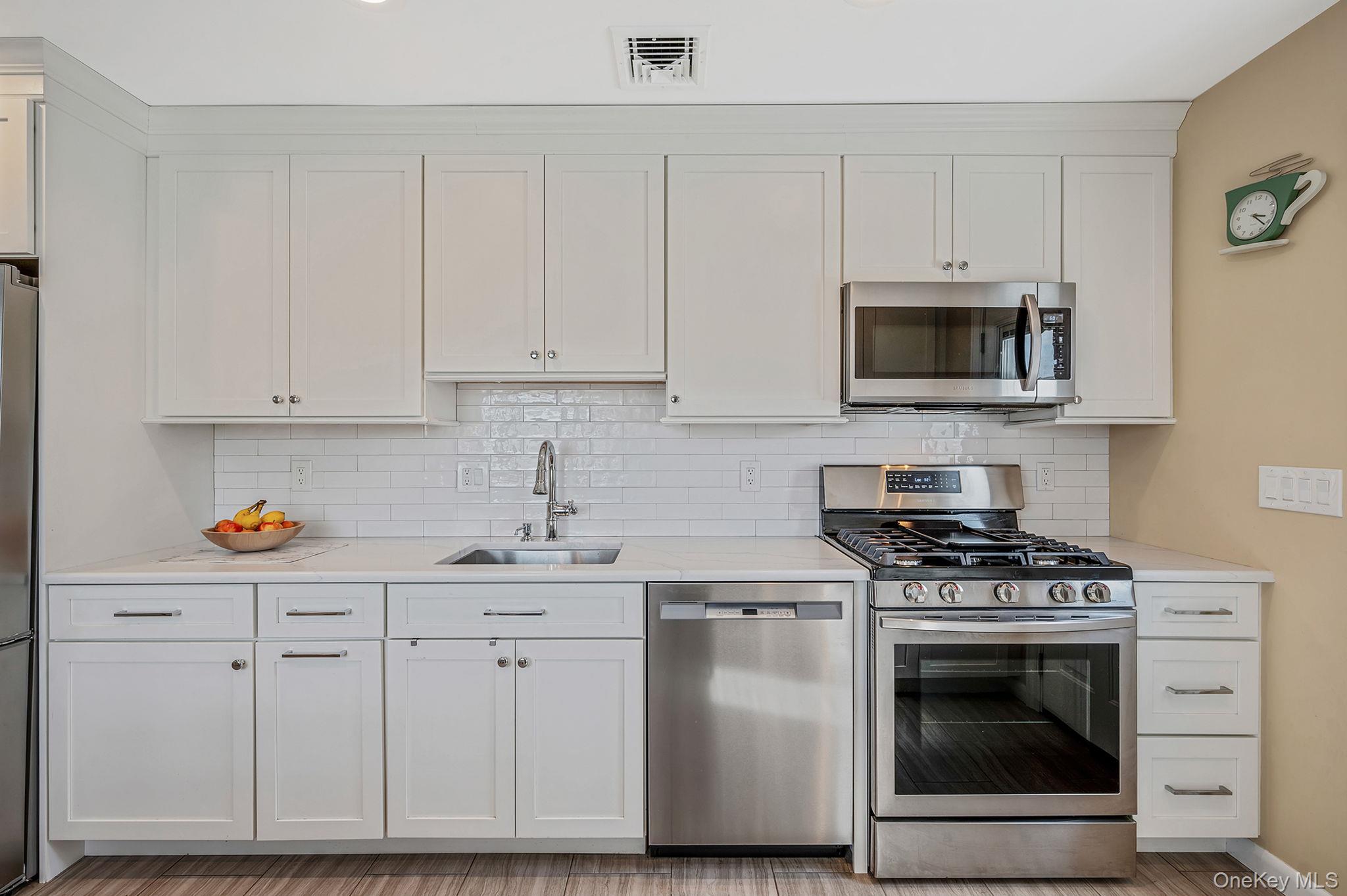 46 Sheldon Place Commack, NY 11725 - Photo 9 of 32 a kitchen with white cabinets and stainless steel appliances