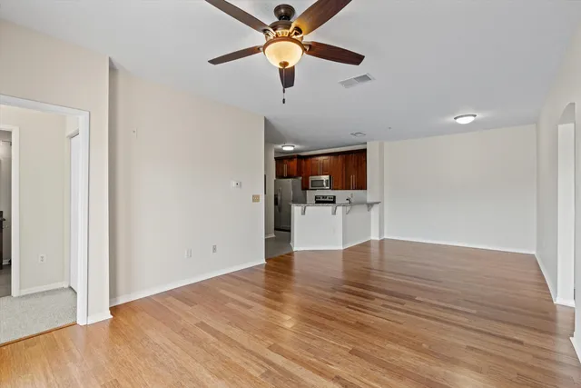 a view of empty room with wooden floor and ceiling fan