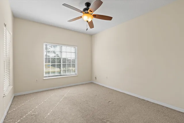 an empty room with a window and a fan