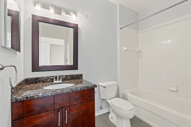 a bathroom with a granite countertop sink toilet mirror and a bathtub