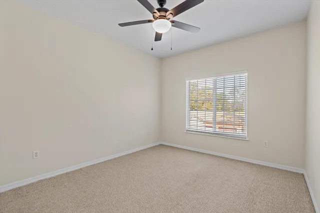 an empty room with a window and a fan