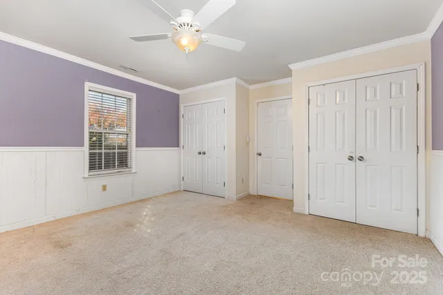 an empty room with chandelier fan and windows