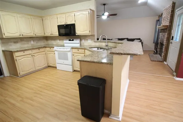 a kitchen with kitchen island granite countertop wooden cabinets and white appliances