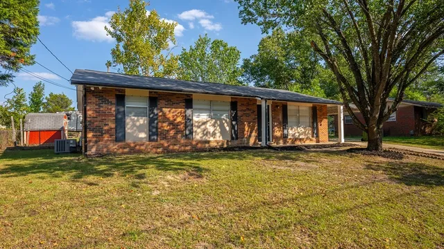 a view of a house with a large tree and a yard