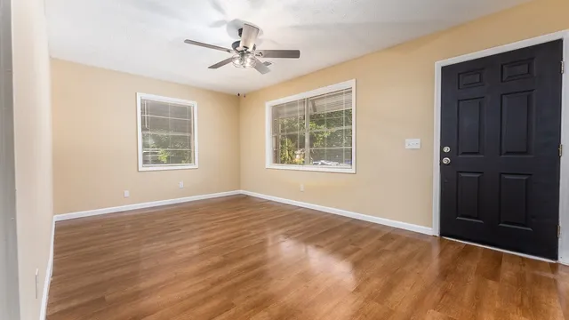 a view of an empty room with a window and wooden floor
