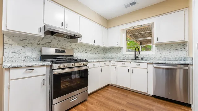a kitchen with granite countertop cabinets stainless steel appliances a sink and window