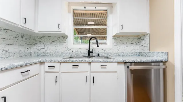 a kitchen with granite countertop a sink and cabinets