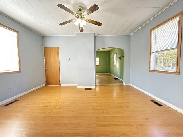 an empty room with wooden floor and windows