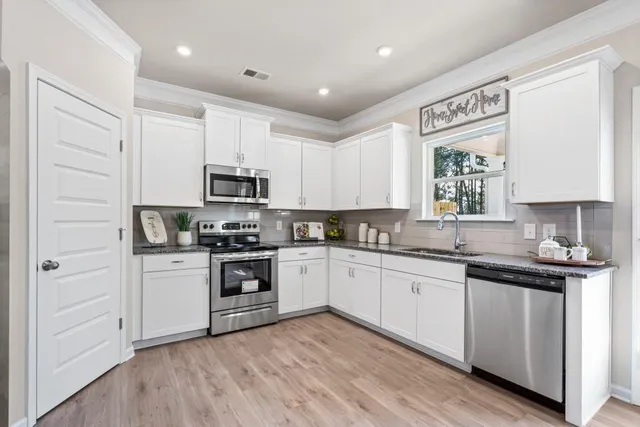 a kitchen with granite countertop white cabinets and window