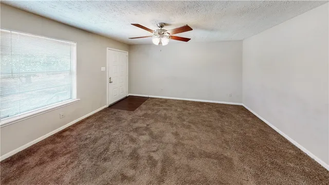 an empty room with a window and a ceiling fan