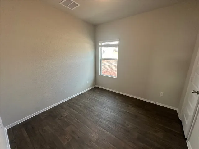 an empty room with wooden floor and window