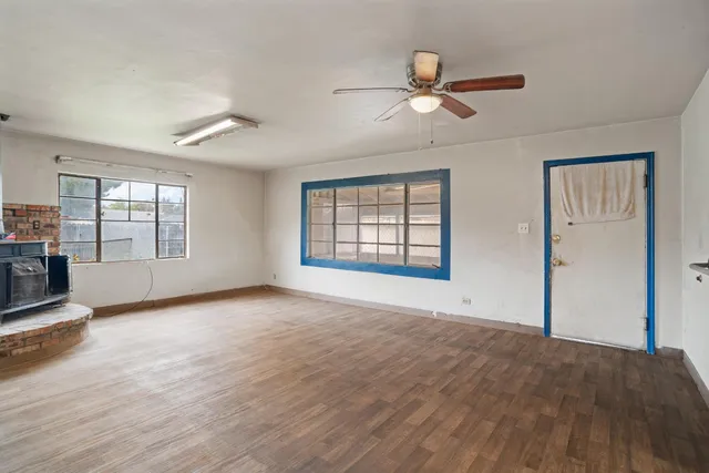 a view of an empty room with a window and wooden floor