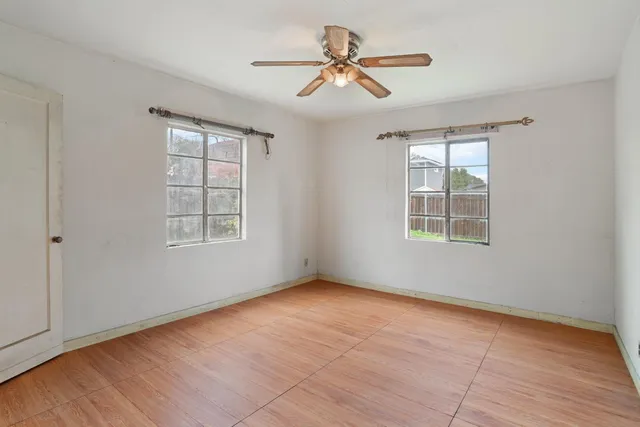 an empty room with windows and fan