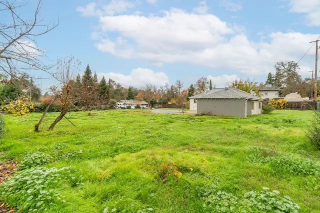 a view of a big house with a big yard and large trees