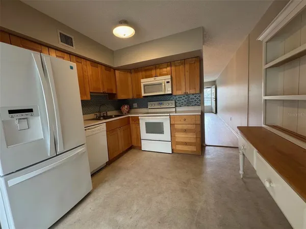 a kitchen with granite countertop a refrigerator and a stove top oven