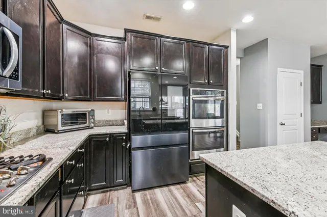 a kitchen with kitchen island granite countertop stainless steel appliances and wooden cabinets