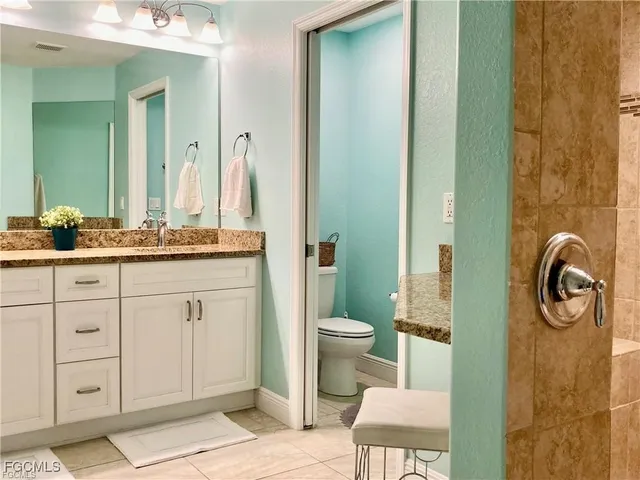 a spacious bathroom with a granite countertop toilet a sink and a mirror