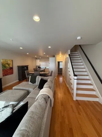 a living room with stainless steel appliances kitchen island granite countertop a refrigerator a stove a sink and a cabinets with wooden floor