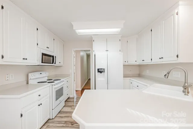 a kitchen with stainless steel appliances a refrigerator sink and white cabinets