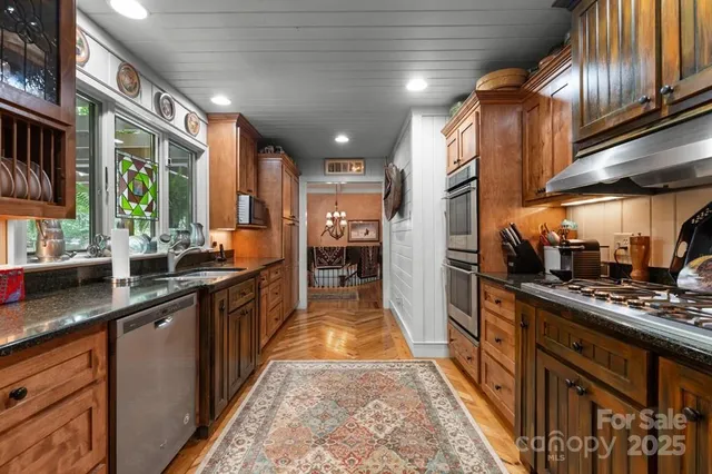a kitchen with stainless steel appliances granite countertop a stove a sink and a microwave