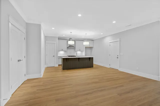 a view of kitchen with kitchen island a sink wooden floor and white cabinets