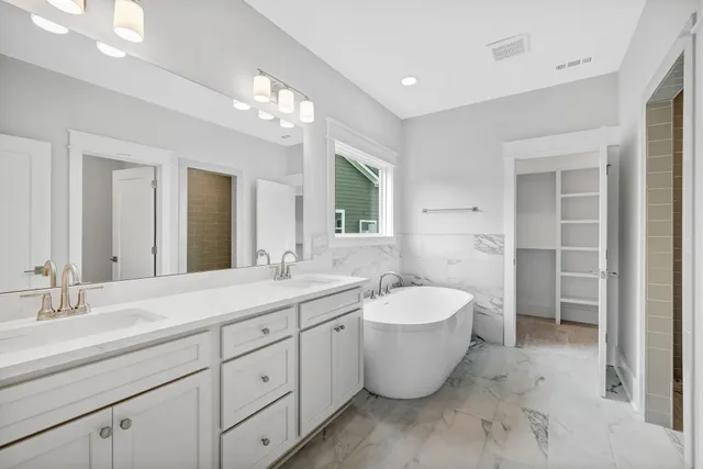 a spacious bathroom with a double vanity sink mirror and bathtub