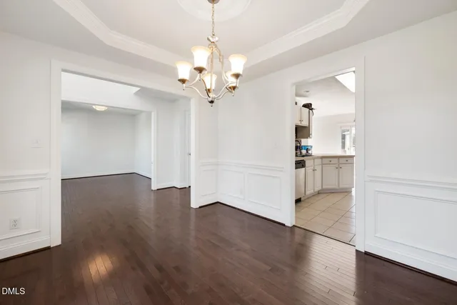an empty room with wooden floor chandelier and windows