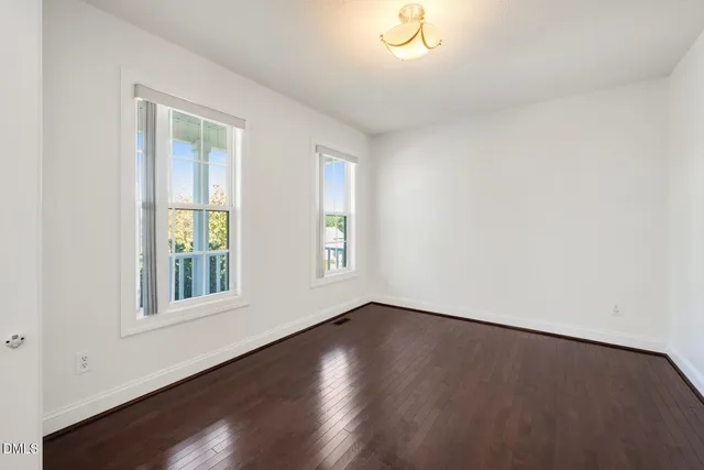an empty room with wooden floor and ceiling fan