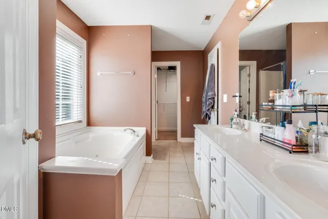 a spacious bathroom with a tub sink and mirror