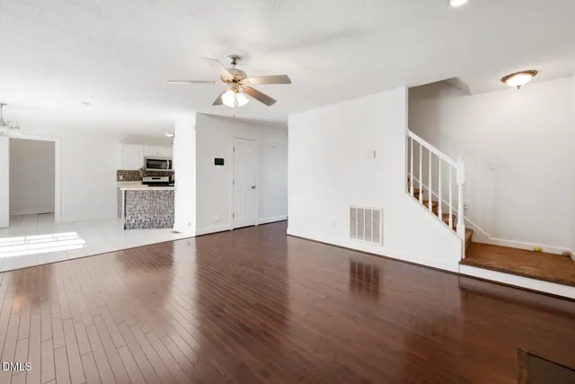 a view of a livingroom with a fireplace a ceiling fan and wooden floor