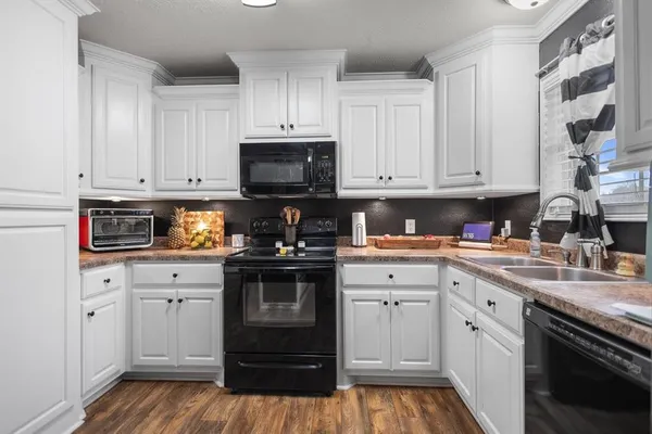 a kitchen with stainless steel appliances kitchen island granite countertop a refrigerator oven a stove top oven and a dining table with wooden floor