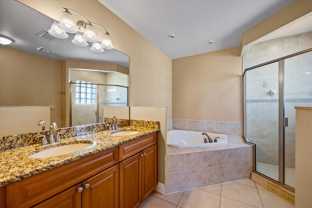 136 175th Avenue East Redington Shores, FL 33708 - Photo 17 of 40 a bathroom with a granite countertop bathtub a sink and a mirror