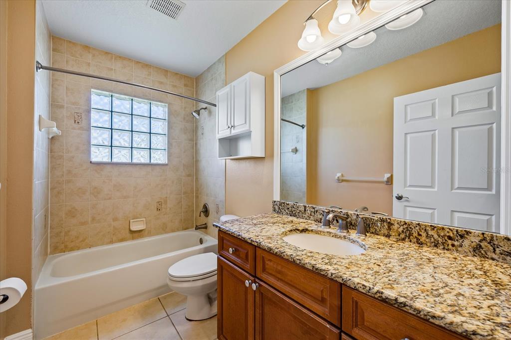 136 175th Avenue East Redington Shores, FL 33708 - Photo 21 of 40 a bathroom with a granite countertop sink toilet mirror and bathtub