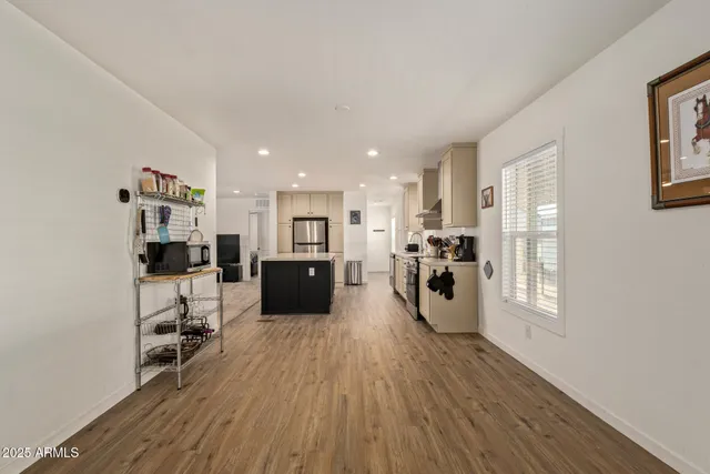 a large kitchen with kitchen island a stove a sink a refrigerator and white cabinets with wooden floor