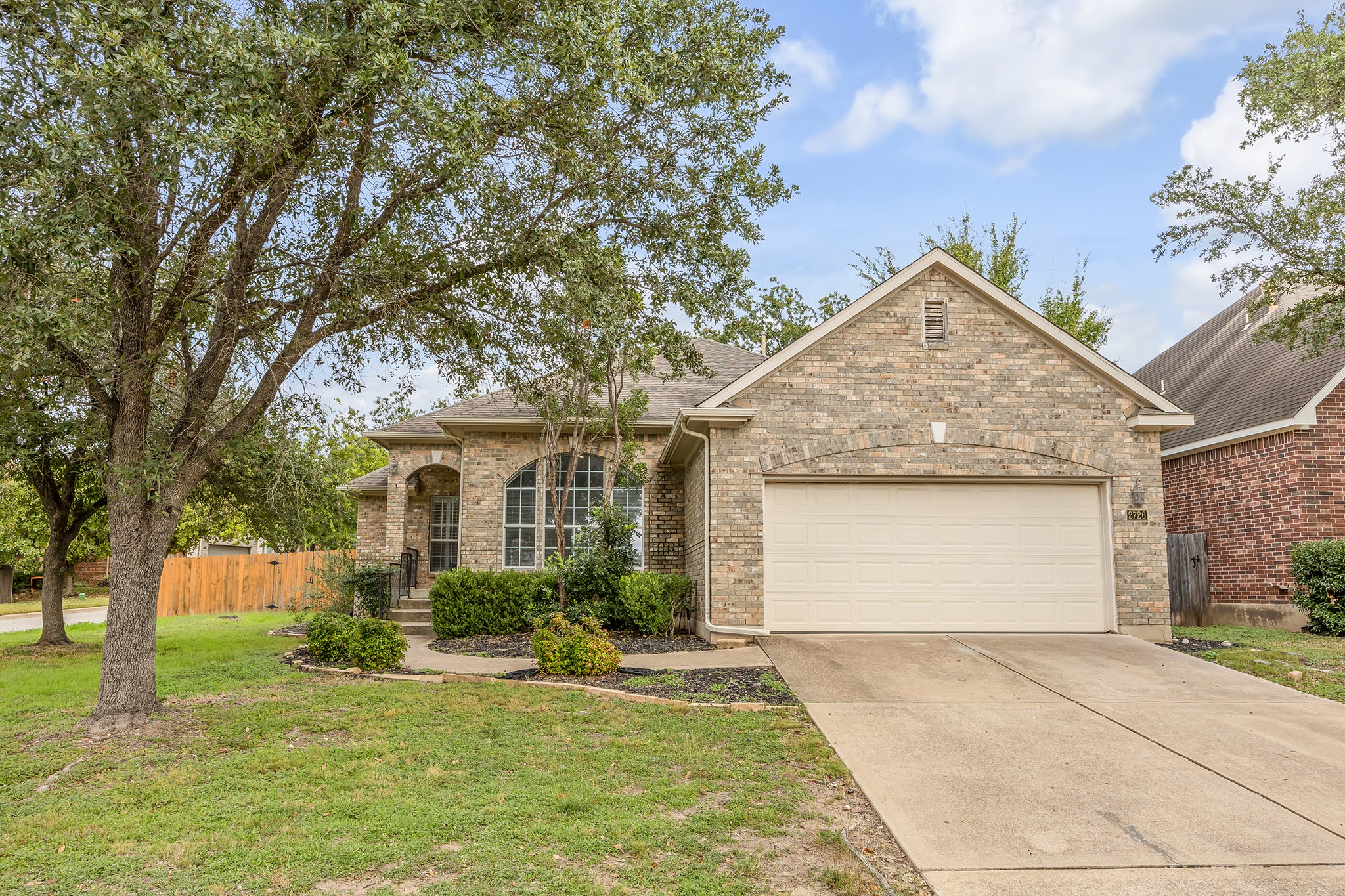 View of front facade with brick siding, concrete driveway, an attached garage, and a shingled roof