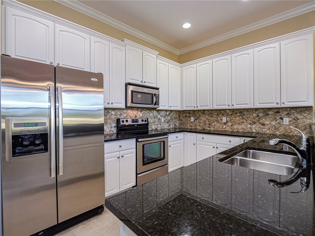 1965 Bridgepointe Circle, Unit 84 Vero Beach, FL 32967 - Photo 11 of 33 a kitchen with white cabinets and stainless steel appliances