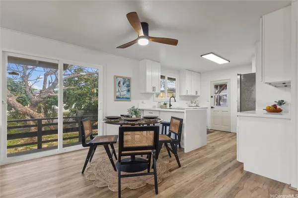 a kitchen with stainless steel appliances kitchen island granite countertop a stove a refrigerator a dining table and chairs with wooden floor