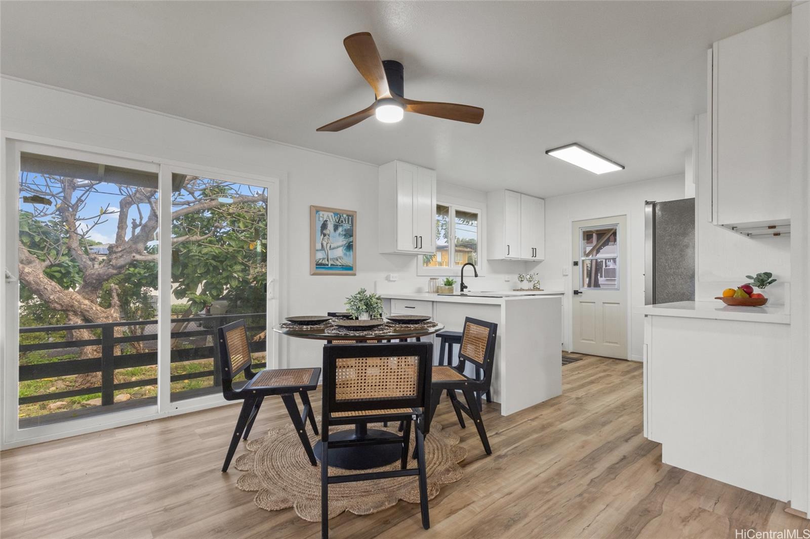 91-433 Ewa Beach Road Ewa Beach, HI 96706 - Photo 2 of 22 a kitchen with stainless steel appliances kitchen island granite countertop a stove a refrigerator a dining table and chairs with wooden floor