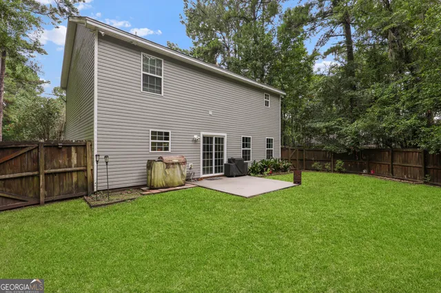 a view of a backyard with plants and large tree